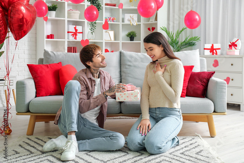 Young man greeting his beloved girlfriend with Valentine's day at home