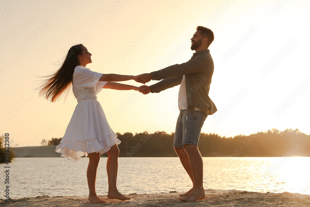 Happy couple dancing near river at sunset Happy couple dancing near river at sunset