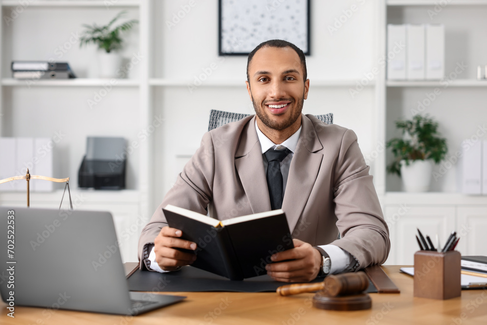 Smiling lawyer with book at table in office