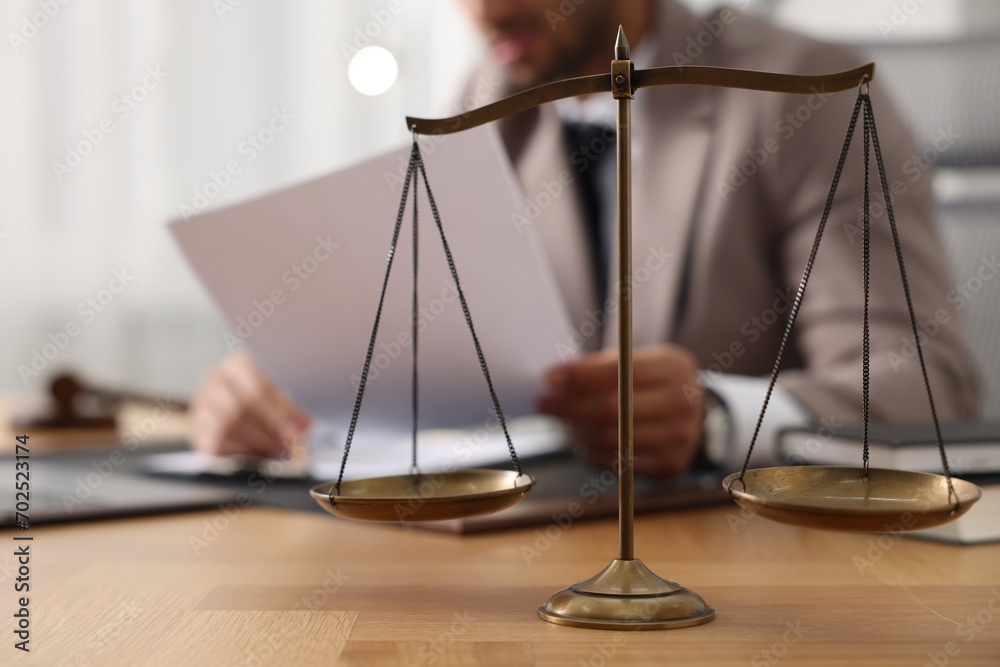 Lawyer working with document at table in office, focus on scales of justice Lawyer working with document at table in office, focus on scales of justice