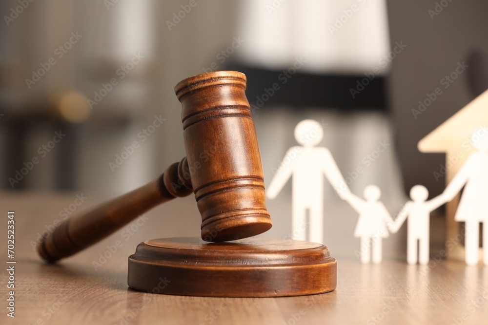 Law concept. Gavel and figures of parents with children on wooden table, closeup Law concept. Gavel and figures of parents with children on wooden table, closeup