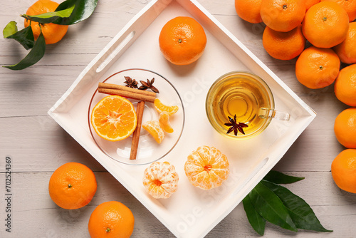 Tray of sweet mandarins, star anise, cinnamon and cup of tea on grey wooden background