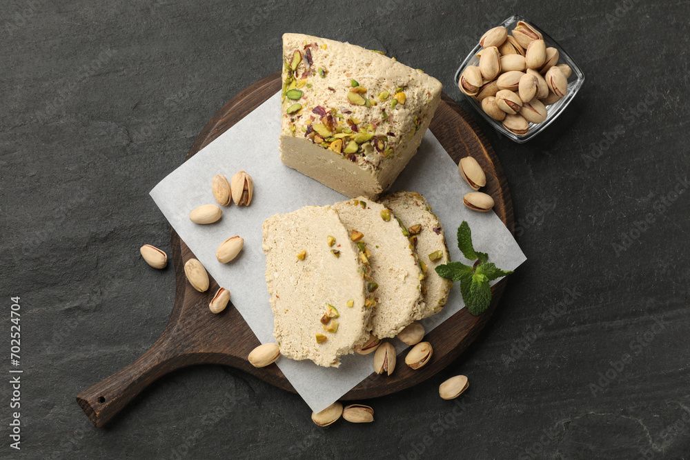 Tasty halva with pistachios and mint on grey table, top view