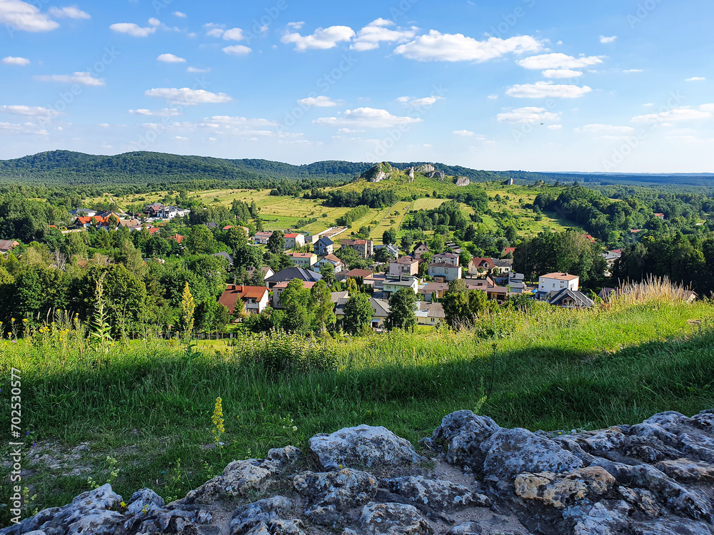 From the top of the Hill, the panoramic view of a small town in the interior of Poland, with its houses amid green trees, grass and a beautiful blue sky, with some clouds.