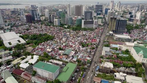 Aerial flyby of a large slum community contrasts with the modern office buildings of Cebu Business Park behind it. photo