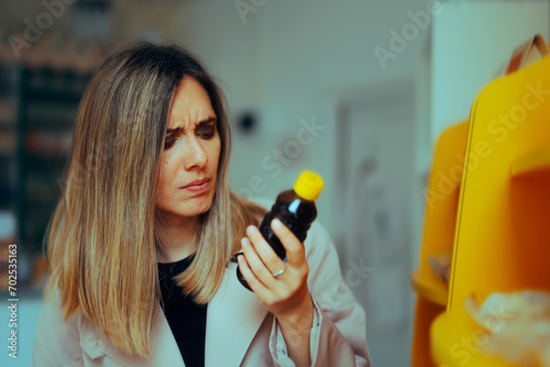 Woman Reading Ingredients on a Bottle of Syrup. Conscious consumer checking ingredient list and expiration date in store 
 photo