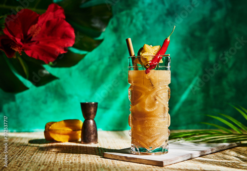 Tropical tiki cocktail with star fruit, lime, and a hot pepper garnish photo