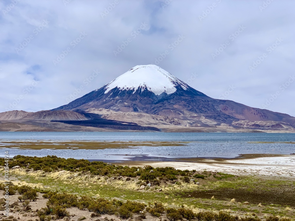 Parinacota dormant stratovolcano in Lauca national park on border of Chile and Bolivia. Snowcapped volcano with Rio Lauca, Lake Chungará and Chilean altiplano in foreground. The Andes at altitude