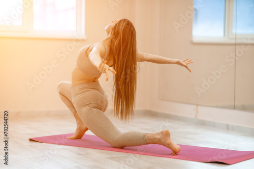 Girl does yoga. Young woman practices asanas on a beige one ton background.