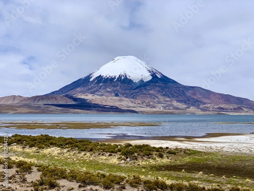 Parinacota dormant stratovolcano in Lauca national park on border of Chile and Bolivia. Snowcapped volcano with Rio Lauca, Lake Chungará and Chilean altiplano in foreground. The Andes at altitude photo