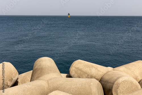Unmanned lighthouse on the breakwater and sea