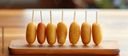 Mini corn dogs made at home, viewed from the side on a wooden board. photo