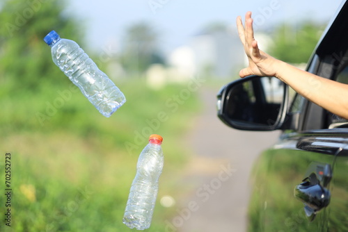 female driver's hand throwing plastic waste on the highway through the car window. bad behavior and habits that damage the environment.