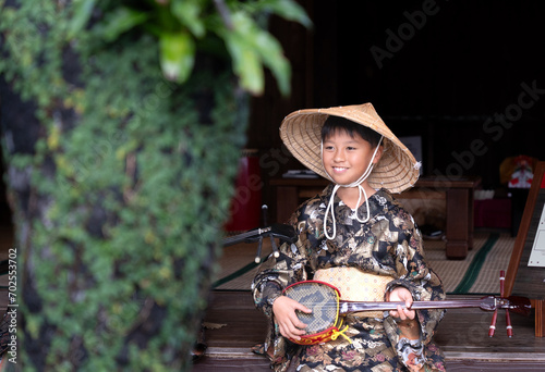 沖縄の民族衣装を着て三線を引く男の子