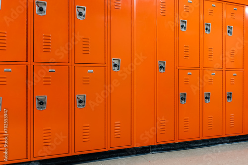 Orange metal lockers along a nondescript hallway in a typical US High School.  No identifiable information included and nobody in the hall. 