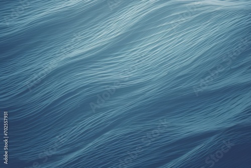 An abstract, close-up texture of ocean waves captured in a soothing blue hue, resembling brush strokes in a painting. The tranquil gradient and flowing patterns invoke the essence of calm sea waters
