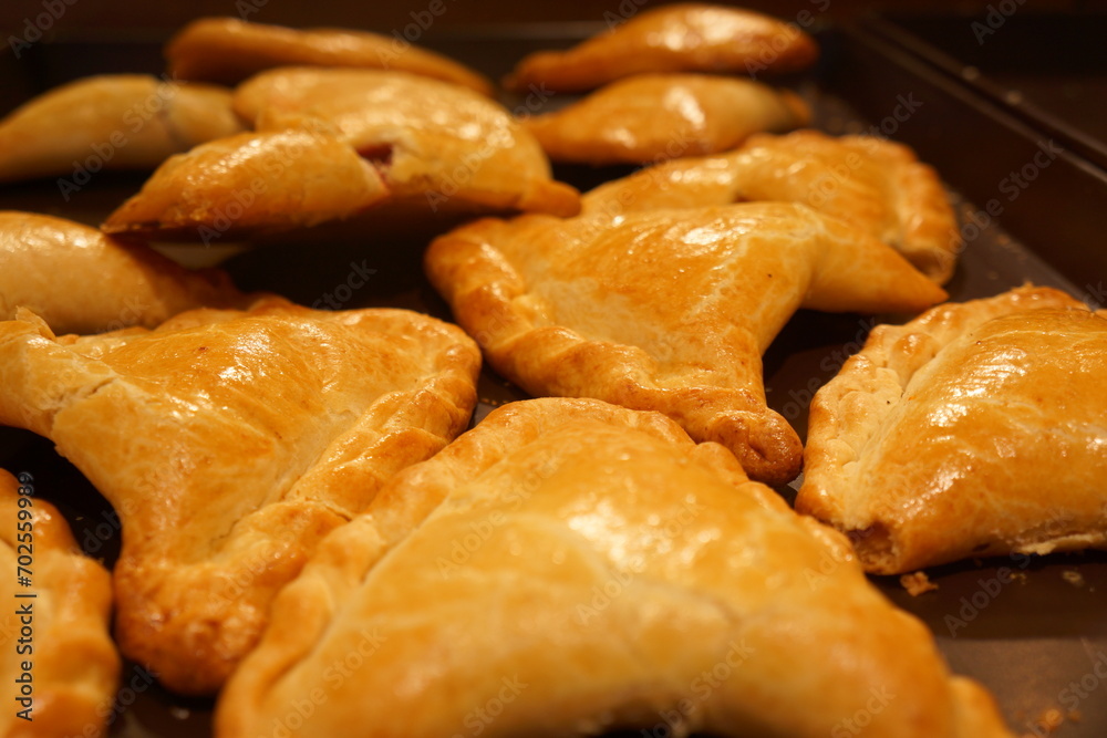 Arrow-shaped crackly pastries under yellowish light, in tray