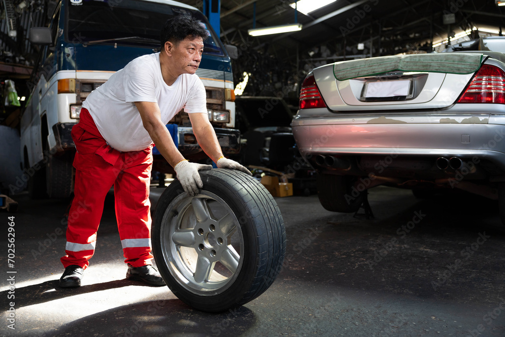 mechanic holding and pushing a tire for fixing in garage mechanic holding and pushing a tire for fixing in garage