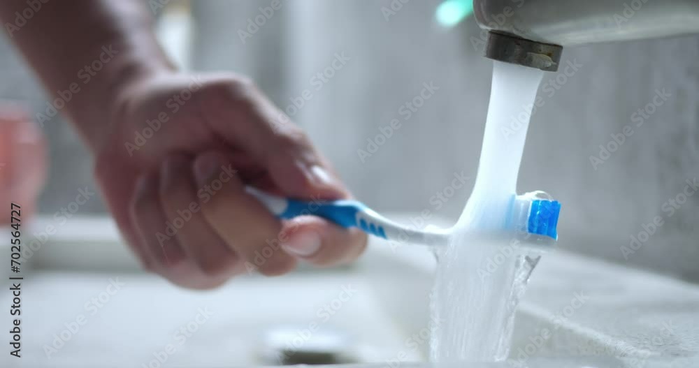 Hand rinsing toothbrush under water. Close up, water flowing in sink from tap, blue brush rinsed under running water to soften bristles and further brush teeth. Man male hand holding toothbrush. Hand rinsing toothbrush under water. Close up, water flowing in sink from tap, blue brush rinsed under running water to soften bristles and further brush teeth. Man male hand holding toothbrush.