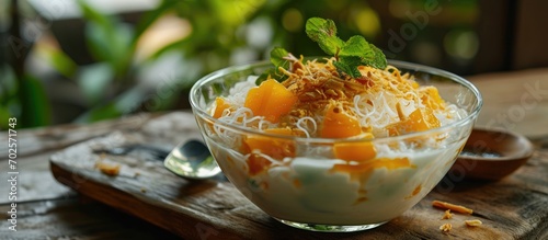Thai dessert of sweet noodles, pumpkin, water chestnuts, and nipa palm fruit in a glass bowl, served with chilled coconut milk.
