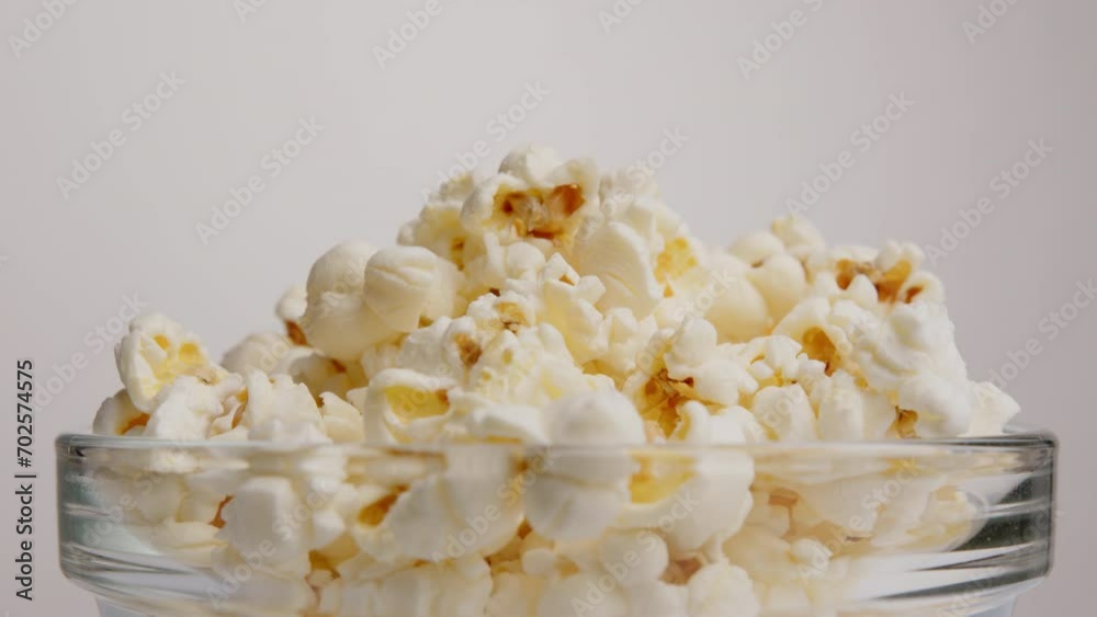 Popcorn close-up in transparent bowl rotating on white background. Popcorn close-up in transparent bowl rotating on white background.