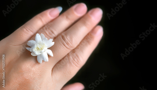A single white jasmine or Arabian jasmine on a female hand in dark background with copy space for text or advertising  banner  business concept