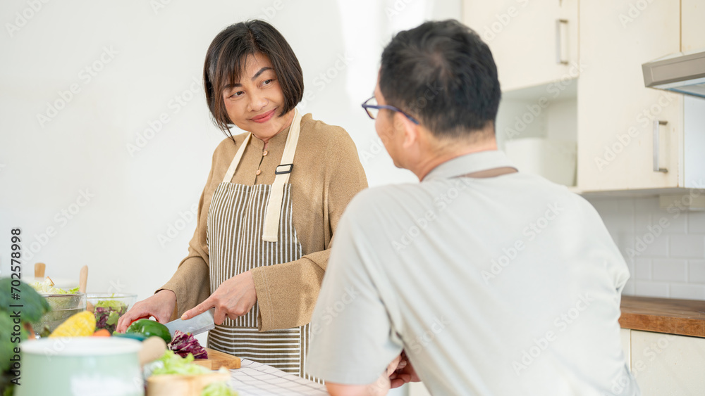 A husband is enjoying talking with his wife while she is cooking breakfast in the kitchen.