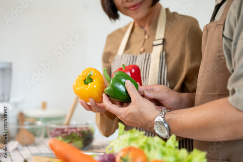A lovely adult couple cooking in the kitchen together, preparing fresh vegetables and ingredients.