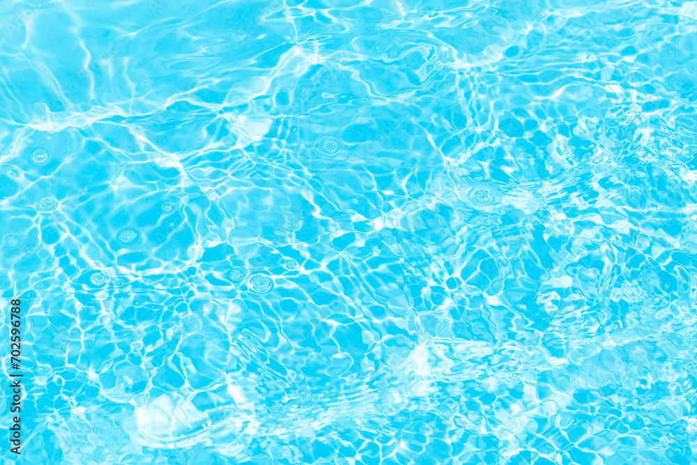 Bluewater waves on the surface ripples blurred. Defocus blurred transparent blue colored clear calm water surface texture with splash and bubbles. Water waves with shining pattern texture background.