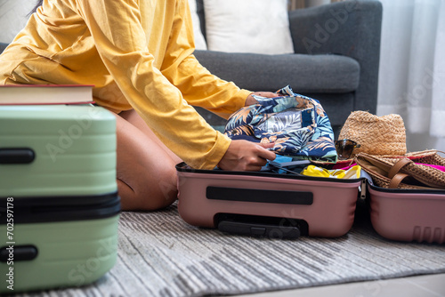 Obraz na plátně Woman opening her suitcase for pack and arranging colorful clothing before trave