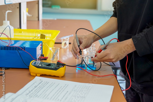 Photos Students use a digital multimeter to measure electrical potential differences in a chemistry experiment on galvanic cells