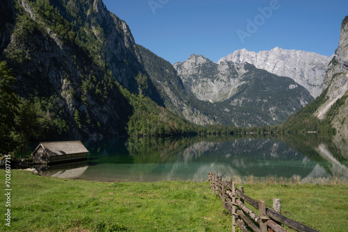 View of Obersee and a wooden cabin and a wooden fence in the foreground. Schönau am Königssee, Germany, Europe. 