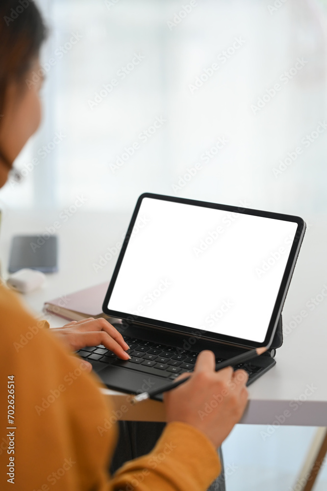 Side view female freelancer working on digital tablet at white desk. Blank screen foe your advertising. Side view female freelancer working on digital tablet at white desk. Blank screen foe your advertising.