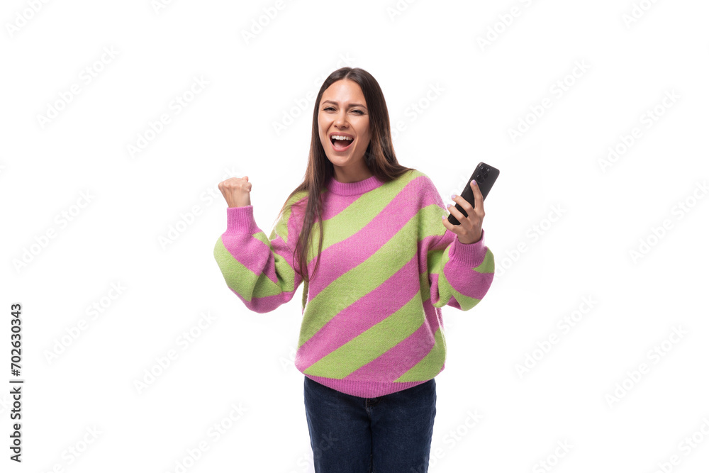 young pretty caucasian woman with black hair dressed in a pink sweater uses a mobile phone on a white background young pretty caucasian woman with black hair dressed in a pink sweater uses a mobile phone on a white background