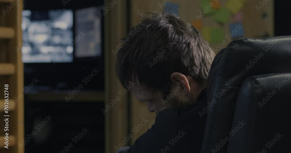 Guard asleep in control room then wakes up to check CCTV monitors, close up Guard asleep in control room then wakes up to check CCTV monitors, close up