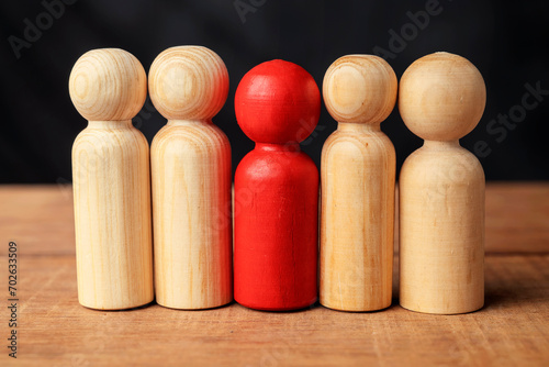 Red wooden figures stand out from the crowd of wooden figures