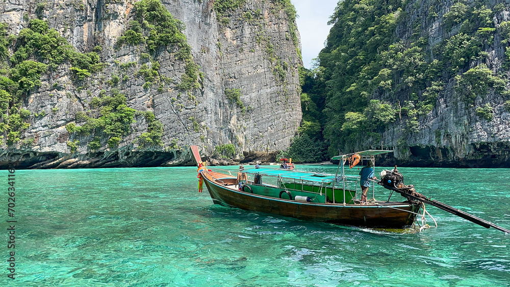 Small wooden tourist boat on a tropical island and clear green water.