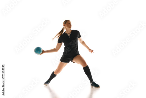 Concentrated female handball player perfecting her throw, highlighting strength and precision against white studio background. Concept of professional sport, movement, dynamic, workout, championship. © Lustre