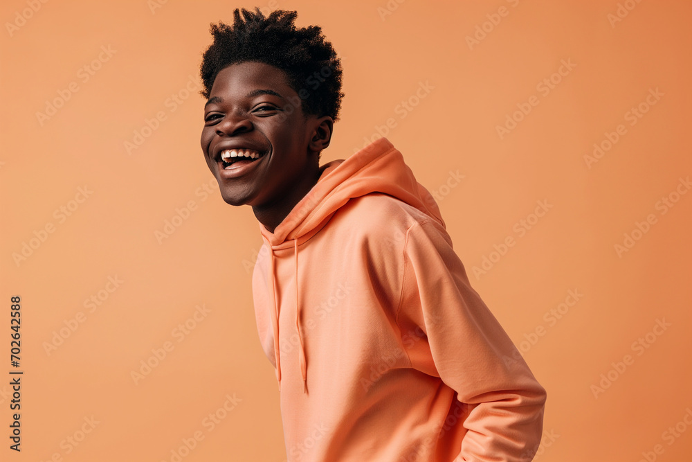 Obraz premium African American happy teenage boy wearing hoodie on peach background