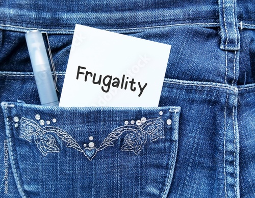 Note and pen in jeans pocket with handwritten note FRUGALITY, latest Trend In Work-Life Balance - accepting lower pay for less-demanding job - Living more frugally to leave stressful job photo