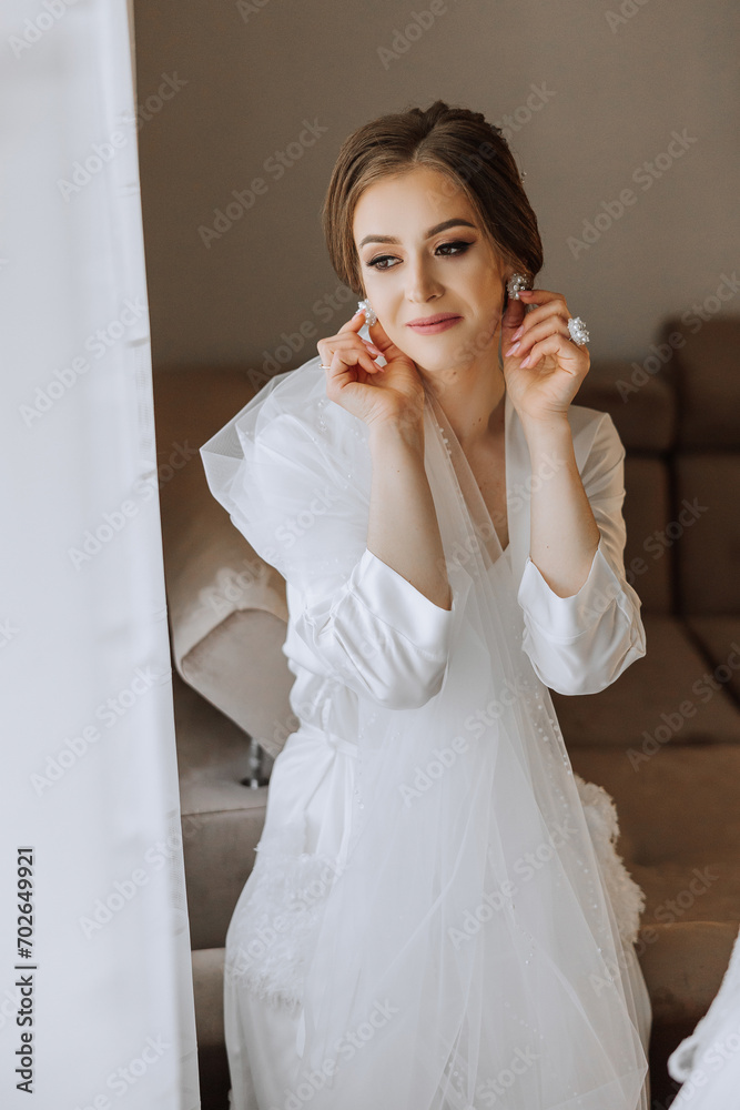 A beautiful brunette bride with a tiara in her hair is getting ready for the wedding in a beautiful robe in boudoir style. Close-up wedding portrait, photo. A beautiful brunette bride with a tiara in her hair is getting ready for the wedding in a beautiful robe in boudoir style. Close-up wedding portrait, photo.