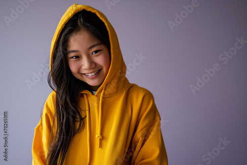 Asian happy teenage girl wearing hoodie on purple background © Darya Lavinskaya