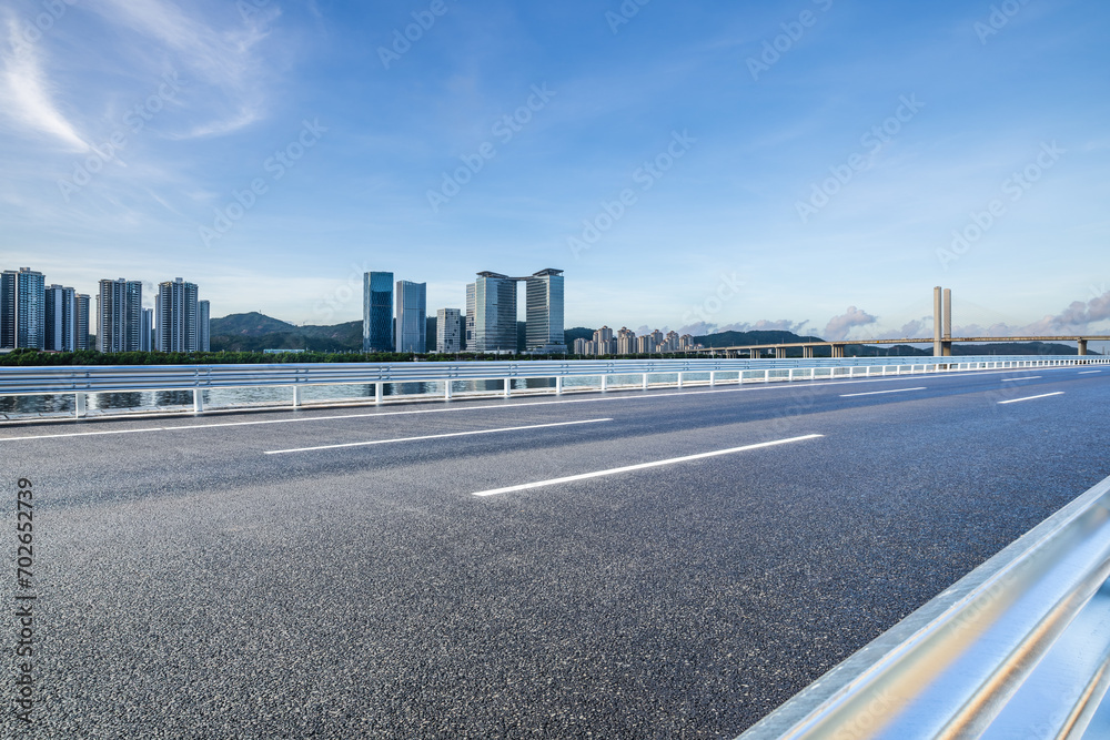Asphalt highway road with modern buildings under blue sky
