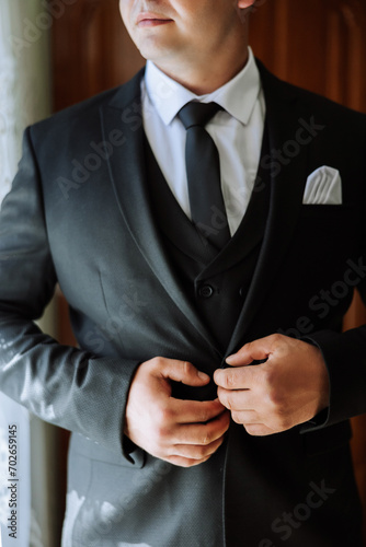 the man fastens the buttons on his jacket. The groom is preparing for the wedding ceremony. Detailed close-up photo of hands