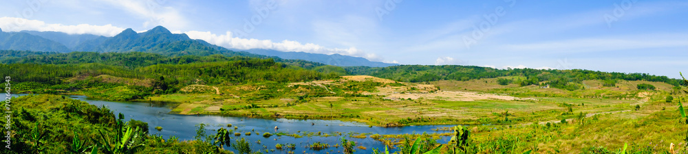 a small lake surrounded by small dry rice fields 