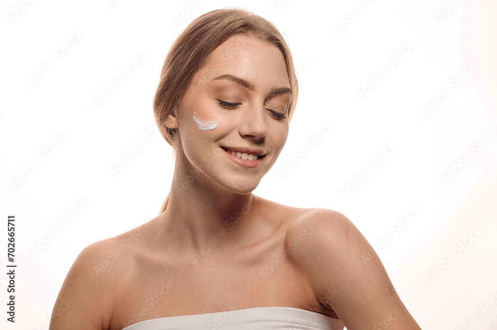 Beauty portrait of a beautiful girl or woman applying cream on her face on an isolated white background Beauty portrait of a beautiful girl or woman applying cream on her face on an isolated white background