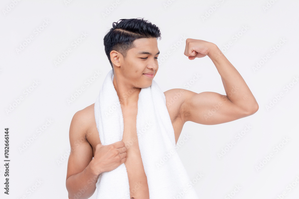 Obraz premium A young asian man with a towel wrapped around his neck, flexing his bicep. Isolated on a white backdrop.
