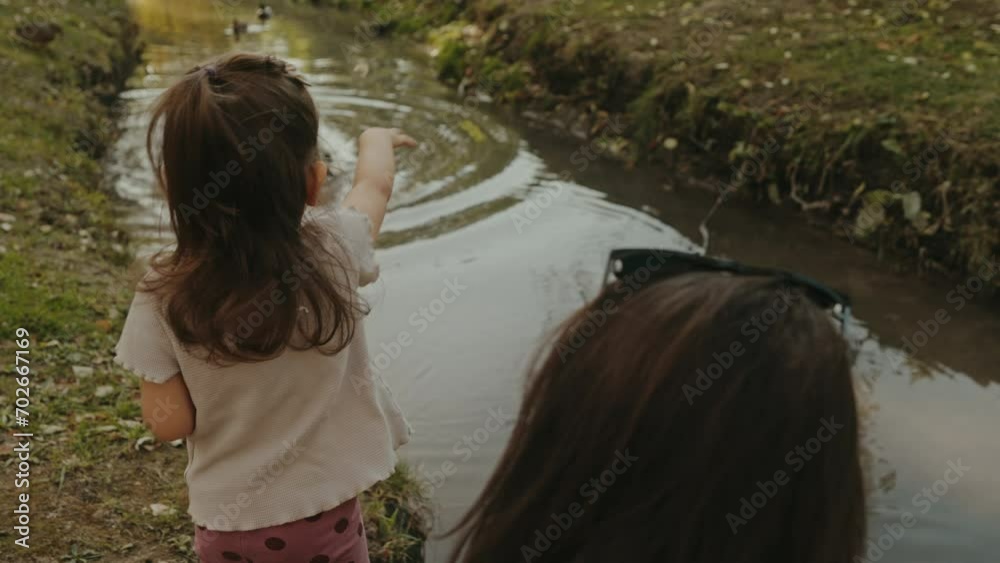 Mother and her adorable daughter girl feeding ducks at summer, in park. Harmonious loving happy family. Love trust. Happy together.Happy childhood. Mother and her adorable daughter girl feeding ducks at summer, in park. Harmonious loving happy family. Love trust. Happy together.Happy childhood.