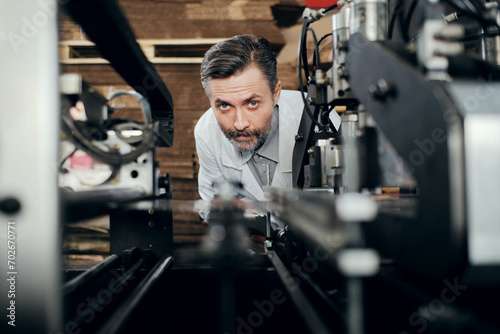 Engineer working at the factory surrounded with machinery, checking equipment