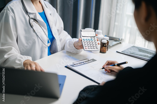Healthcare costs and fees concept.Hand of smart doctor used a calculator and smartphone, tablet for medical costs photo
